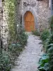 Bruniquel - Paved lane lined with plants and door of a stone house 