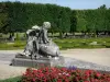 Champs-sur-Marne城堡 - 法国花园：前景中的鲜花，雕像，刺绣床和树木