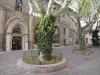 Embrun - Ancien couvent des Cordeliers abritant l'office de tourisme et place Général Dosse agrémentée de platanes (arbres) et de fleurs