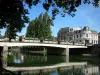 Melun - Flower-covered bridge spanning the River Seine, facades of the city and trees along the water