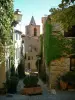 Гримо - Склонная аллея средневековой деревни, дома с фасадами, покрытыми вьющимися растениями, и колокольня церкви Сен-Мишель на заднем плане