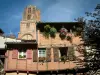 Albi - Casa de ladrillo con paredes de madera con flores y una torre campanario de la Catedral de Santa Cecilia