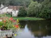 Angles-sur-l'Anglin - Flowers in foreground, Anglin river, boats, trees along the water and houses of the village