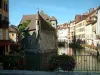 Annecy - Ponte decorada com flores com vista para o Palais de l'Île (antigas prisões) que abriga o Museu da História de Annecy, o canal de Thiou e suas aves aquáticas, o cais da ilha (margem do rio) e casas para fachadas coloridas da cidade velha