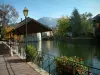 Annecy - Flower-bedecked bank with a lamppost, the Thiou canal, trees, houses of the old town and mountain in background