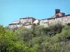 Antraigues-sur-Volane - Vista da torre do sino da igreja de Saint-Baudile e as casas da aldeia empoleirada rodeada por vegetação; no Parque Natural Regional de Monts d'Ardèche