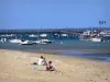 Arcachon bay - Vacationers sitting on a beach in the seaside resort of Cap Ferret, boats, Bélisaire pier and its jetty in the background; in the town of Lège-Cap-Ferret 