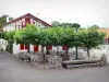 Arcangues - White house with red shutters and restaurant terrace shaded by plane trees