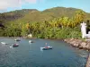 Barque cove - Lighthouse of the Barque cove, trees and coconut trees along the sea and boats floating on the water; inbetween the towns of Vieux-Habitants and Bouillante, on the island of Basse-Terre