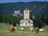 Basílica de Saint-Just de Valcabrère - Vacas en un prado en el primer plano, basílica románica, los árboles, la Catedral de San Bertrand de Comminges en el fondo y la colina de Comminges