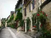 Beynac-et-Cazenac - Sloping narrow street of the village and its stone houses with facades decorated with climbing roses, in the Dordogne valley, in Périgord