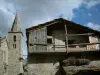 Bonneval-sur-Arc - Antigua casa de piedra con su balcón de madera, el campanario de la iglesia del pueblo de Saboya y el cielo nublado, en la Haute-Maurienne (Mont Blanc)