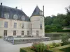 Castillo de Bussy-Rabutin - Macizo de flores en el jardín francés con vistas al foso, la fachada del edificio principal y una de las torres redondas del castillo