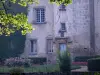 Castillo de Les Martinanches - Escalera de la torre y la fachada del castillo, jardín con flores y ramas de un árbol en la ciudad de Saint-Dier-d'Auvergne