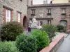Céret - Front of the Céret tourist office and statue of the sitting Catalan surrounded by flowers and shrubs