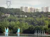 Cergy-Pontoise leisure island - Nautical activities on one of the ponds (body of water) of the domain, trees at the edge of the water, and houses and buildings in the background