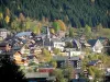 Châtel - View of the village (winter and summer sports resort) with its chalets, its residences and its church, trees in autumn and spruce forest in Chablais