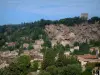 Cotignac - Los árboles, las casas de pueblo, las ruinas del castillo (la ciudad) y el acantilado de toba perforado por cuevas