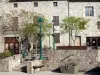 Désaignes - Plaza de la Fuente, con árboles y farolas, oficina de turismo de entrada y fachadas de piedra de la villa medieval