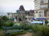 Dinard - Station balnéaire de la côte d'Émeraude : banc et fleurs en premier plan, villa, immeubles et commerces