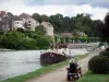 Dole - Canal du Rhône au Rhin avec des péniches amarrées, rive agrémentée d'un banc, immeuble, maisons de la ville et arbres
