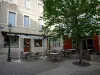 Embrun - Lugar de Mazelière: cafetería, árbol, farola y fachadas de las casas en el casco antiguo