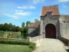 Fief des Epoisses stronghold - Entrance to the old medieval fortified farm, moats, lawn and trees; in the town of Bombon