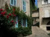 Figeac - Climbing rosebush (red roses), narrow street and stone houses of the old town, in the Quercy