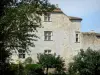 Fourcès - Fachada del castillo perforado con ventanas geminadas y follaje de los árboles