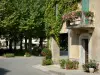 Fourcès - Casa decorada con flores y la plaza redonda la sombra de los plátanos (árboles)