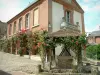 Gerberoy - Flower-bedecked well, brick-built house (town hall and museum) and climbing rosebushes (red roses)