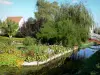 Hortillonnages de Amiens - Jardín de flores adornado con árboles y flores a lo largo del agua y el pequeño puente sobre el canal