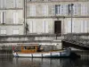 Jarnac - Wooden boat moored to the quay, Charente river and facades of houses