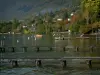 Lac d'Annecy - Lac avec pontons en bois, bateau et bouées, maisons, arbres et forêt en automne