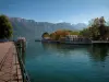 Lac d'Annecy - À Annecy : quai Napoléon III (berge), embarcadère (port) avec des bateaux amarrés, arbres aux couleurs de l'automne, lac et montagnes en arrière-plan
