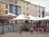 Leucate - Leucate village, in the Regional Natural Park of Narbonne in the Mediterranean: Place de la République square with its colorful facades and café terraces shaded by umbrellas