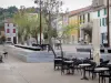 Leucate - Leucate village: facades of houses, trees and café terraces of the Place de la République square