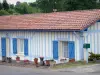 Lévignacq - Casa blanca con persianas azules de madera y decorado con macetas de flores