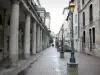 Lons-le-Saunier - Ronde street with the columns of the theatre, lampposts, shops and facades of houses