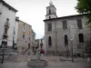 Manosque - San Salvador, la Iglesia y su campanario rematado por una campana, una fuente y las casas en el casco antiguo