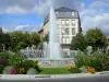 Millau - Fountain of the Mandarous square, flowers and buildings of the town