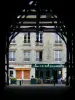 Milly-la-Forêt - Under the covered market hall, view of a café terrace and facade of a house in the village