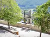 Montbrun-les-Bains - Banco rodeado de árboles con vistas a la torre de la iglesia y al verde paisaje circundante