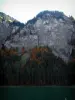 Montriond lake - Lake, spruces, trees in autumn, cliffs and waterfall in Haut-Chablais