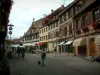 Obernai - Calle peatonal con casas de madera adornadas con flores (geranios), cafetería y tiendas