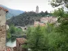 Olargues - Casa de piedra en el primer plano con vista de la torre del campanario, las casas del pueblo, el puente sobre el río y los árboles a la orilla del agua, en el Parque Natural Regional del Alto Languedoc