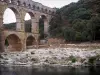 Puente del Gard - Acueducto romano (monumento antiguo), con tres pisos (niveles) de arcadas (arcos), la costa bordeada de árboles y Gardon río, en la ciudad de Vers-Pont-du-Gard