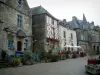 Rochefort-en-Terre - Calle bordeada de casas antiguas: hay madera, otro tiene una torreta, algunos de ellos con fachadas de granito. Plantas y arbustos.