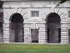 The royal saltworks of Arc-et-Senans - Royal saltworks of Arc-et-Senans: Arches of the portico of a building of the former saltworks and a lawn dotted with flowers