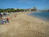 Sainte-Maxime - Plage de sable, parasols et transats avec des estivants, mer méditerranée, voiliers (bateaux) du port de plaisance, pins parasols, palmiers, maisons et immeubles de la station balnéaire